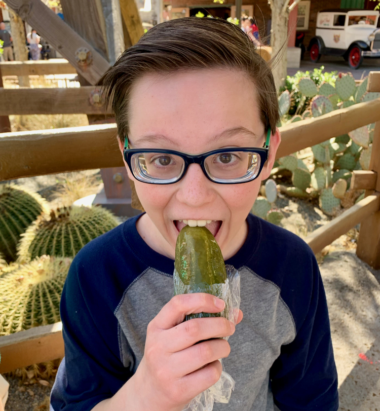 boy biting into a giant pickle
